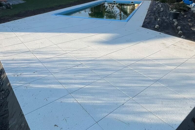 Plaża basenowa z jasnych płyt wielkoformatowych wokół basenu