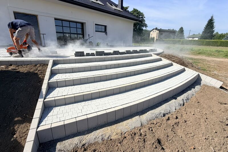 Schody zewnętrzne o łukowym kroju z jasnej kostki brukowej